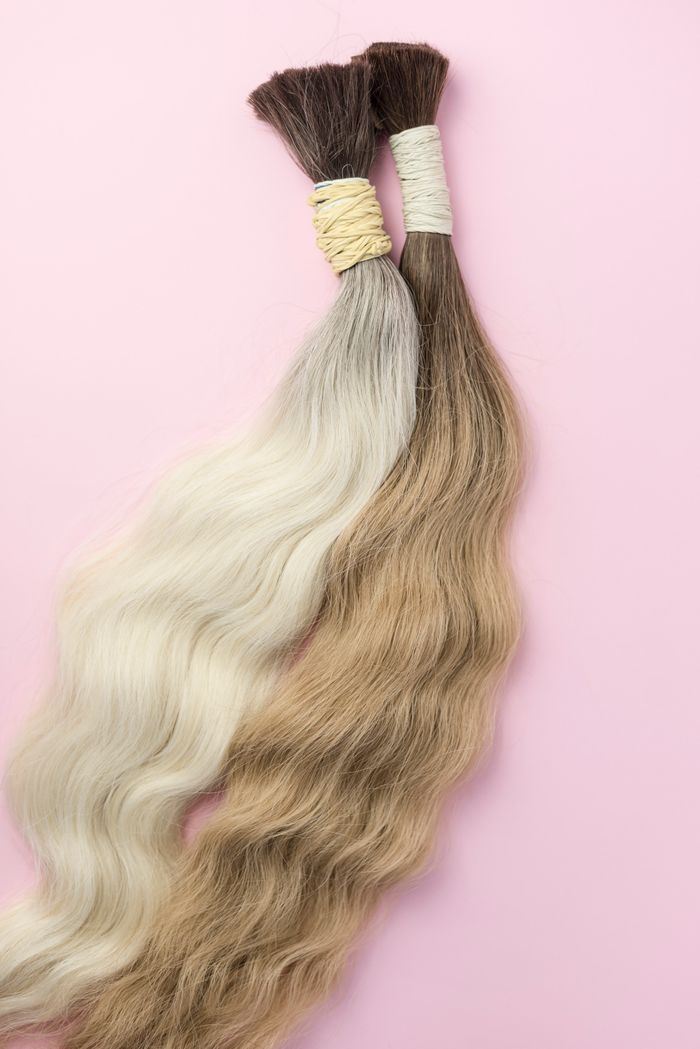 Two elegant hair extensions in contrasting colors on a soft pink backdrop.